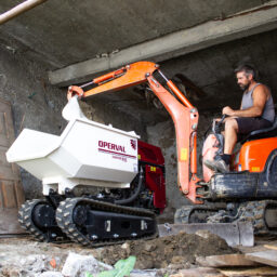 Un mini dumper per edilizia durante la movimentazione di sabbia e pietrisco in un cantiere urbano